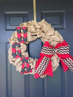 a burlock wreath with red and black chevron ribbon hanging on the front door