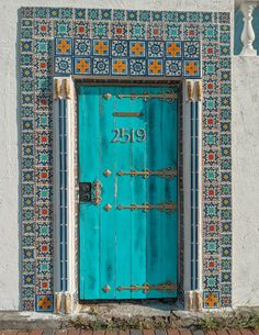 a blue door that is on the side of a building with decorative tile around it