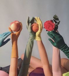 four hands in gloves hold apples and roses above their heads, while the other hand holds an apple