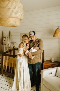 a man and woman standing next to each other in a room with a crib