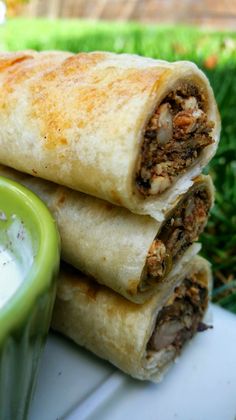 two burritos stacked on top of each other next to a green bowl