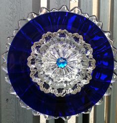 a blue glass plate sitting on top of a wooden table next to a metal fence