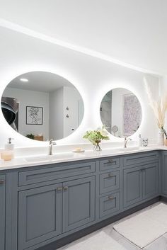 a large bathroom with two sinks and mirrors on the wall, along with three round mirrors