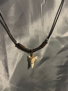 a necklace with an animal charm hanging from it's side on a white cloth