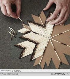 two hands are working on an ornament made out of matches and wood sticks