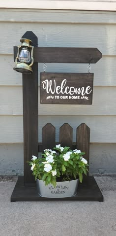 a potted plant sitting on top of a wooden stand next to a welcome sign