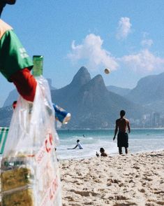 a man standing on top of a beach next to a bag of sand and water