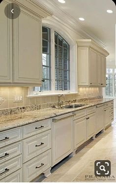 a large kitchen with white cabinets and marble counter tops