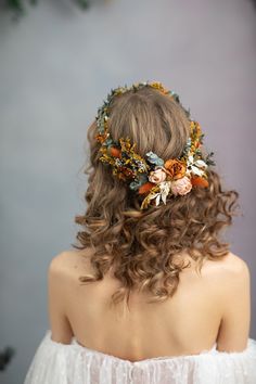 the back of a woman's head with flowers in her hair, wearing a white dress