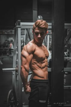 a shirtless man standing in front of a gym machine with his hands on his hips