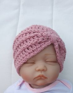 a baby doll wearing a pink crochet hat on top of it's head