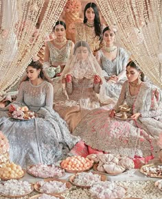 a group of women sitting next to each other on top of a floor covered in food