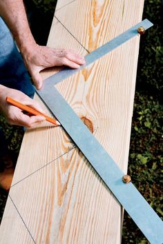 a person cutting wood with a large pair of scissors on top of the board that is being cut