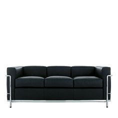 a black leather couch sitting on top of a white floor next to a metal frame