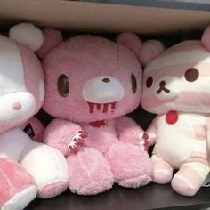 several stuffed animals are on display in a store shelf, one is pink and the other is white