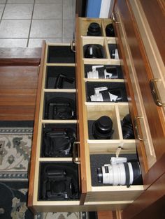 an open drawer with many cameras in it