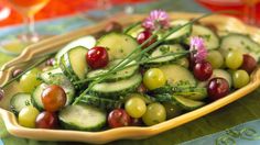 cucumber and grapes salad in a yellow bowl on a tablecloth with wine glasses