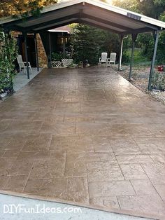 an empty patio in the middle of a yard with chairs around it and trees on either side