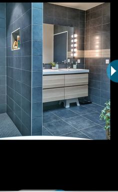 an image of a bathroom setting with blue tiles on the walls and floor, along with a large mirror over the sink