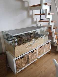 a fish tank sitting on top of a wooden floor next to some baskets and stairs