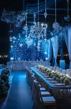 a long table is set up with white flowers and chandeliers hanging from the ceiling