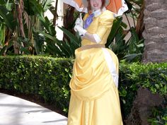 a woman in a yellow dress holding an orange umbrella