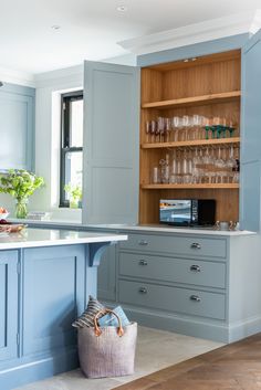 a kitchen with blue cabinets and an island in front of the countertop is filled with wine glasses