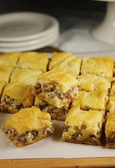 several pieces of meat filled pastry sitting on top of a white plate with one slice cut out