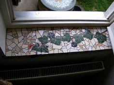 a bathroom window with a mosaic tile floor next to a toilet and sink in it