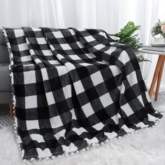 a black and white checkered blanket sitting on top of a couch next to a table