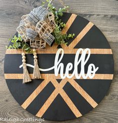 a wooden sign with the word hello painted on it and some greenery in front of it