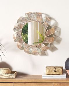 a mirror hanging on the wall above a dresser with a basket and plant in it