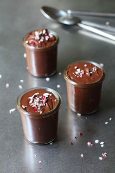 three small jars filled with chocolate pudding and sprinkles on top of a table