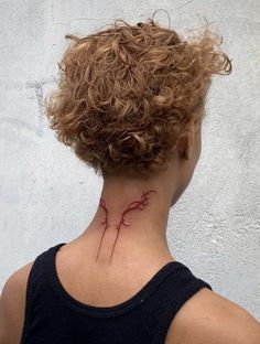 the back of a woman's neck with a red tattoo on her left side