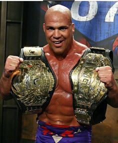 a man in purple wrestling trunks holding up two gold rings