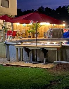 an outdoor patio with umbrellas and tables in the background at night, surrounded by lawn furniture