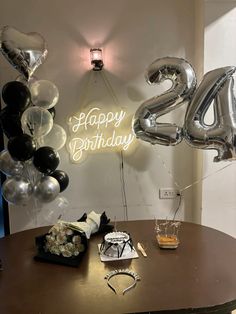 a table with balloons and gifts on it in front of a sign that says happy birthday