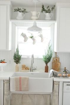 a kitchen with white cabinets and an old fashioned sink in the center is decorated for christmas