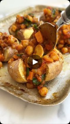 a spoon scooping some food out of a baked potato on top of a plate