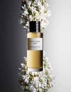 a bottle of perfume sitting on top of a bouquet of white flowers with a black cap