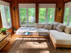 a living room filled with lots of furniture next to large window covered in wood planks