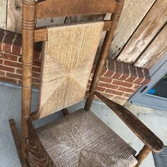 a wooden rocking chair sitting on top of a cement floor next to a brick wall