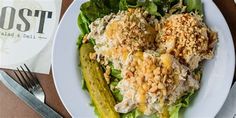 a white plate topped with salad and cucumbers next to silverware on a table