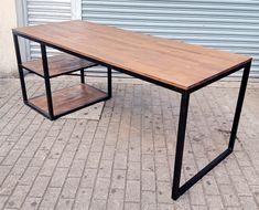 a wooden table sitting on top of a brick floor next to a metal frame wall