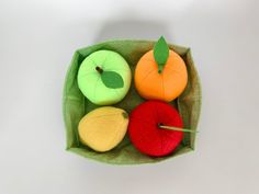 four apples and two oranges are in a green cloth bag on a white surface