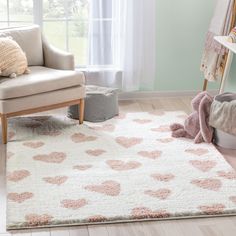 a pink rug with white hearts on it in front of a couch and chair next to a window