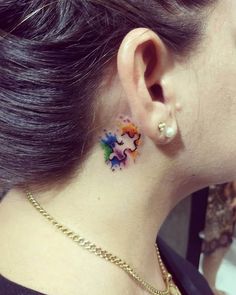 a woman's left ear has a colorful dragon tattoo on it and is wearing a gold chain