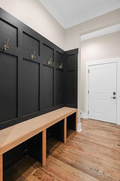 a wooden bench sitting in front of a wall with coat hooks on it's sides