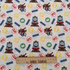 thomas the tank engine on white fabric with red, yellow and blue letters that read'the fabric squirrel '