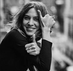 a black and white photo of a smiling woman with her hand on her head,